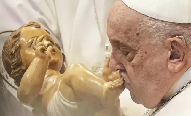 Pope Francis kisses a wooden statuette of the infant Jesus at the end of a mass in St. Peter's Basilica at The Vatican on New Year's Day, Wednesday, Jan. 1, 2025. (AP Photo/Andrew Medichini)