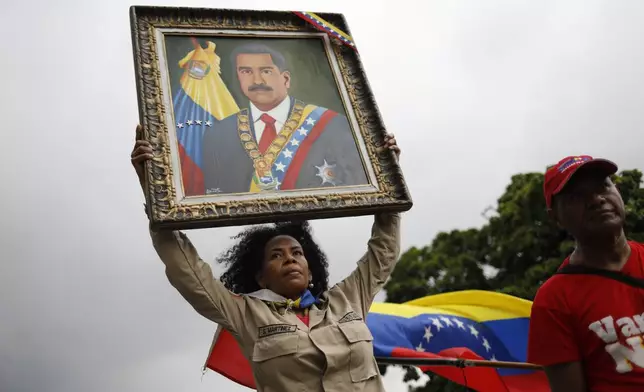 FILE - A member of the Bolivarian Militia holds up a painting depicting President Nicolas Maduro during a rally celebrating Maduro's July 28 reelection, in Caracas, Venezuela, Sept. 28, 2024. (AP Photo/Cristian Hernandez, File)