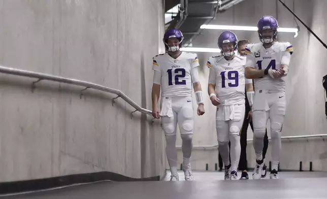 Minnesota Vikings quarterbacks Nick Mullens (12), Brett Rypien (19) and Sam Darnold (14) walk to the field before an NFL football game against the Detroit Lions, Sunday, Jan. 5, 2025, in Detroit. (AP Photo/Rey Del Rio)