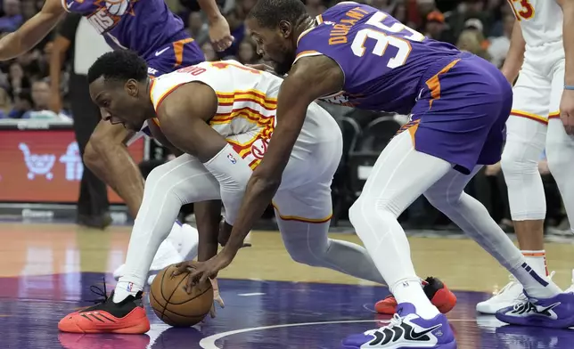 Atlanta Hawks forward Onyeka Okongwu, left, battles with Phoenix Suns forward Kevin Durant (35) for the ball during the first half of an NBA basketball game Thursday, Jan. 9, 2025, in Phoenix. (AP Photo/Ross D. Franklin)