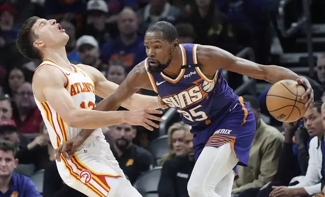 Phoenix Suns forward Kevin Durant (35) fouls Atlanta Hawks guard Bogdan Bogdanovic, left, during the first half of an NBA basketball game Thursday, Jan. 9, 2025, in Phoenix. (AP Photo/Ross D. Franklin)