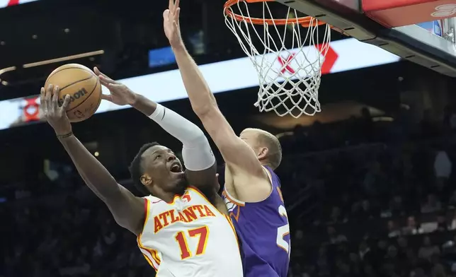 Atlanta Hawks forward Onyeka Okongwu (17) drives past Phoenix Suns center Mason Plumlee , right, to score during the first half of an NBA basketball game Thursday, Jan. 9, 2025, in Phoenix. (AP Photo/Ross D. Franklin)