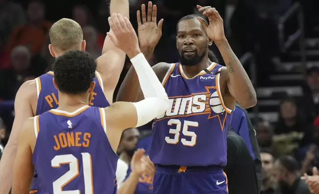 Phoenix Suns forward Kevin Durant (35) celebrates his 3-pointer against the Atlanta Hawks with Suns guard Tyus Jones (21) and Suns center Mason Plumlee during the first half of an NBA basketball game Thursday, Jan. 9, 2025, in Phoenix. (AP Photo/Ross D. Franklin)