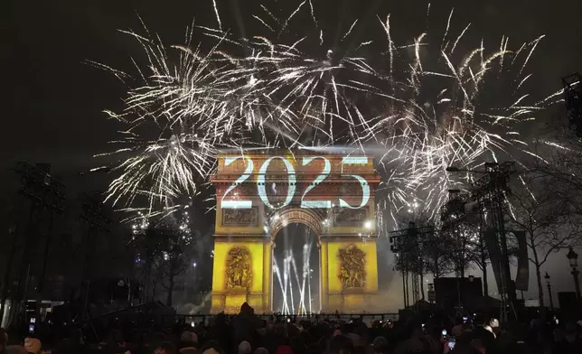 A light show is projected on the Arc de Triomphe as fireworks explode during New Year celebrations on the Champs Elysees in Paris, France, Wednesday, Jan. 1, 2025. (AP Photo/Thibault Camus)