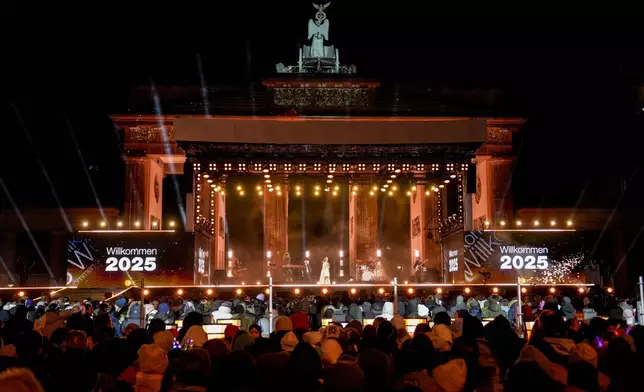 People gather near the Brandenburg Gate to celebrate and watch the fireworks for the New Year's celebrations in Berlin, Germany, Tuesday, Dec. 31, 2024. (AP Photo/Ebrahim Noroozi)