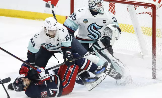 Seattle Kraken's Jamie Oleksiak (24) defends against Winnipeg Jets' Nino Niederreiter (62) as Kraken goaltender Joey Daccord (35) watches the puck during second-period NHL hockey game action in Winnipeg, Manitoba, Thursday, Jan. 16, 2025. (John Woods/The Canadian Press via AP)