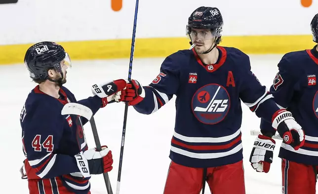 Winnipeg Jets' Josh Morrissey (44) and Mark Scheifele (55) celebrate after Scheifele's goal against the Seattle Kraken during second-period NHL hockey game action in Winnipeg, Manitoba, Thursday, Jan. 16, 2025. (John Woods/The Canadian Press via AP)