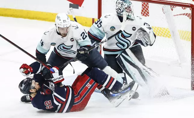 Seattle Kraken's Jamie Oleksiak (24) defends against Winnipeg Jets' Nino Niederreiter (62) as Kraken goaltender Joey Daccord (35) watches the puck during second-period NHL hockey game action in Winnipeg, Manitoba, Thursday, Jan. 16, 2025. (John Woods/The Canadian Press via AP)