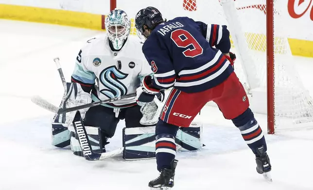 Winnipeg Jets' Alex Iafallo (9) looks for a rebound off Seattle Kraken goaltender Joey Daccord, left, during second-period NHL hockey game action in Winnipeg, Manitoba, Thursday, Jan. 16, 2025. (John Woods/The Canadian Press via AP)