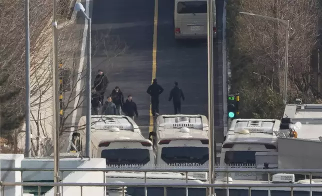 Security personnel walk on a road lined up with buses blocking the entrance gate of impeached South Korean president Yoon Suk Yeol's residence in Seoul, South Korea, Wednesday, Jan. 8, 2025. (AP Photo/Ahn Young-joon)