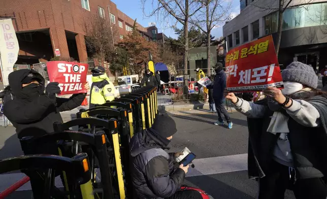 Demonstrators supporting, left, and opposing impeached South Korean President Yoon Suk Yeol confront each other near the presidential residence in Seoul, South Korea, Wednesday, Jan. 8, 2025. The letters on right read "Arrest Yoon Suk Yeol." (AP Photo/Ahn Young-joon)