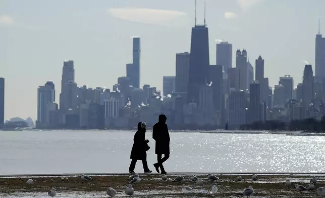 Pedestrians bundle up as they walk along the shore of Lake Michigan at Montrose beach during cold weather in Chicago, Wednesday, Jan. 8, 2025. (AP Photo/Nam Y. Huh)