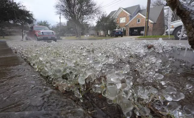 Cold temperatures and a lawn sprinkler create ice on grass ahead of a winter storm expected to hit the North Texas region later tomorrow Wednesday, Jan. 8, 2025, in Richardson, Texas. (AP Photo/LM Otero)