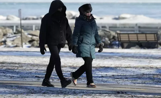 Pedestrians bundle up as they take a walk during cold weather in Evanston, Ill., Wednesday, Jan. 8, 2025. (AP Photo/Nam Y. Huh)