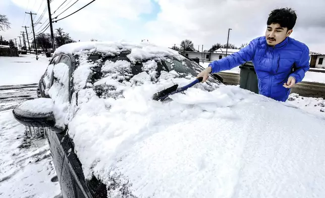 University of Louisville student Alex Hernandez scrapes the ice and snow from the front windshield of his car, Wednesday, Jan. 8, 2025, in Owensboro, Ky, while getting the vehicle ready to drive back to the college after being home for winter break. (Greg Eans/The Messenger-Inquirer via AP)