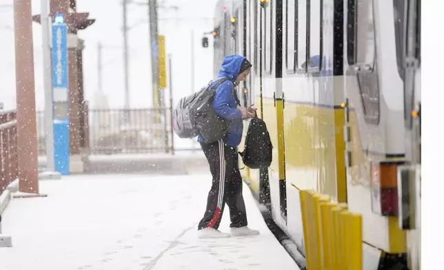 Snow falls as a person boards a DART train Thursday, Jan. 9, 2025, in Dallas. (AP Photo/LM Otero)