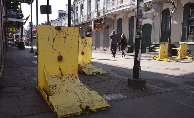 Tourist walk past temporary barriers on Bourbon Street, Thursday, Jan. 2, 2025 in New Orleans. (AP Photo/George Walker IV)