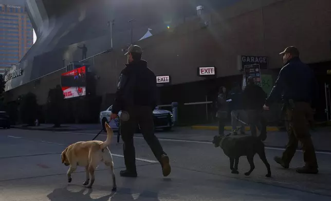 Security with bomb sniffing dogs patrol the area around the Superdome ahead of the Sugar Bowl NCAA College Football Playoff game, Thursday, Jan. 2, 2025, in New Orleans. (AP Photo/Butch Dill)