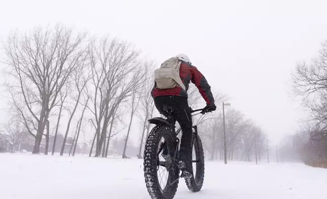 A cyclist rides through a park in Montreal, Wednesday, Jan. 8, 2025. (Christinne Muschi/The Canadian Press via AP)