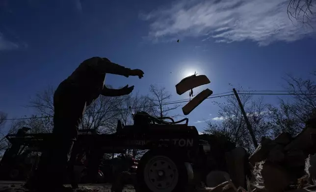 Sterling Howard tosses firewood to prepare for sale ahead of a winter storm expected to hit the North Texas region later tomorrow Wednesday, Jan. 8, 2025, in Dallas. (AP Photo/LM Otero)