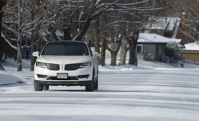 A lone vehicle moves along ice-covered Bonnie Brae Boulevard as a winter storm sweeps over the intermountain West and across the country Tuesday, Jan. 7, 2025, in Denver. (AP Photo/David Zalubowski)