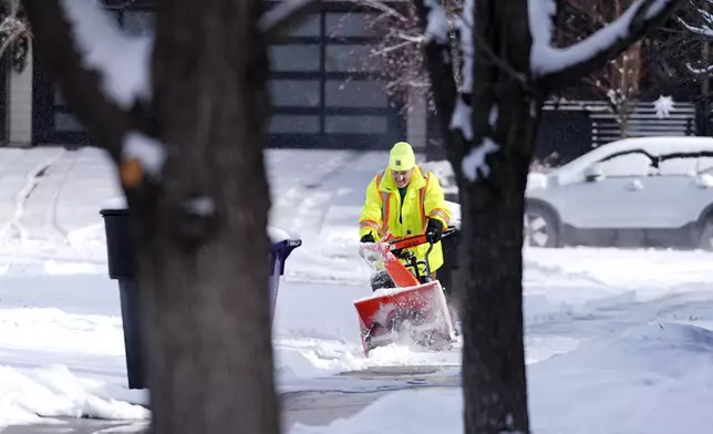 A man uses a snowblower to clear a sidewalk as a winter storm sweeps over the intermountain West and across the country Tuesday, Jan. 7, 2025, in Denver. (AP Photo/David Zalubowski)