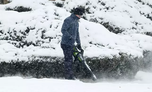 A man uses a blower to clear snow from a sidewalk as a winter storm sweeps over the intermountain West and across the country Tuesday, Jan. 7, 2025, in southeast Denver. (AP Photo/David Zalubowski)