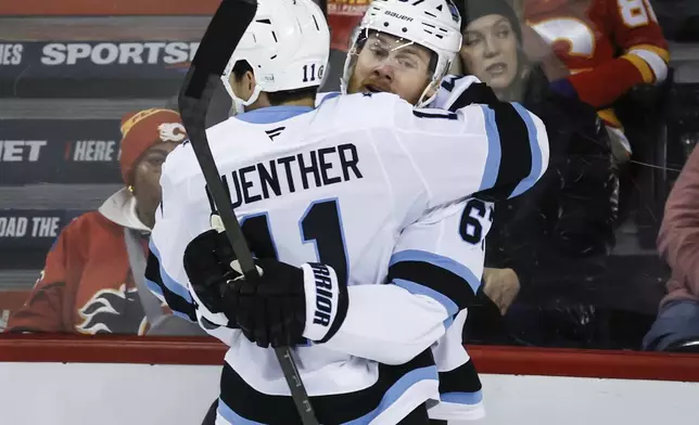 Utah Hockey Club's Lawson Crouse, right, celebrates his goal with teammate Dylan Guenther during the third period of an NHL hockey game against the Calgary Flames in Calgary, Alberta, Thursday, Jan. 2, 2025. (Jeff McIntosh/The Canadian Press via AP)