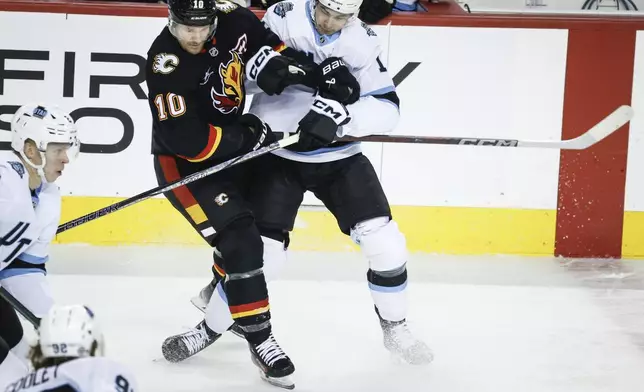 Utah Hockey Club's Dylan Guenther, right, checks Calgary Flames' Jonathan Huberdeau during the first period of an NHL hockey game in Calgary, Alberta, Thursday, Jan. 2, 2025. (Jeff McIntosh/The Canadian Press via AP)