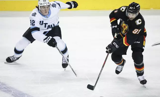 Utah Hockey Club's Logan Cooley, left, and Calgary Flames' Nazem Kadri race for the puck during the first period of an NHL hockey game in Calgary, Alberta, Thursday, Jan. 2, 2025. (Jeff McIntosh/The Canadian Press via AP)