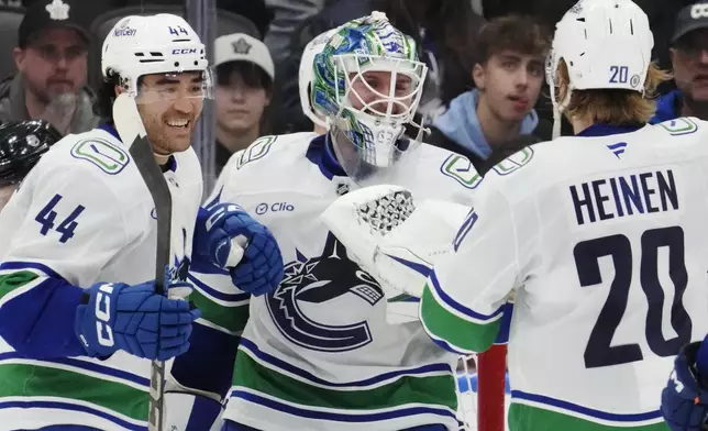 Vancouver Canucks goaltender Kevin Lankinen (centre) celebrates with Kiefer Sherwood (44) and Danton Heinen (20) after defeating the Toronto Maple Leafs in NHL hockey action in Toronto on Saturday, Jan. 11, 2025. (Frank Gunn/The Canadian Press via AP)