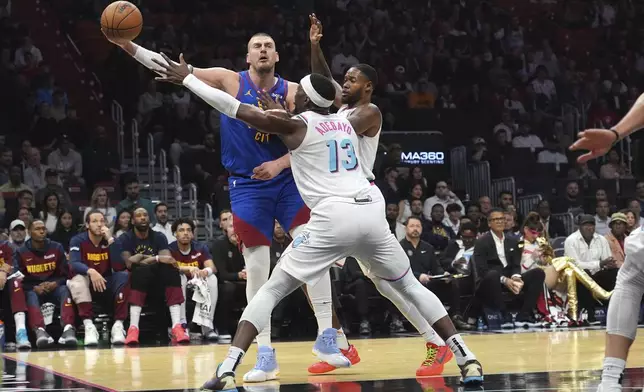 Denver Nuggets center Nikola Jokic, left, passes as Miami Heat center Bam Adebayo (13) defends during the first half of an NBA basketball game, Friday, Jan. 17, 2025, in Miami. (AP Photo/Lynne Sladky)