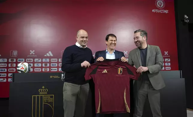 Newly appointed coach for Belgium's national team Red Devils, Rudi Garcia, center, holds a national team jersey as he poses with sports director Vincent Mannaert, right, and CEO Peter Willems after a media conference in Tubize, Friday, Jan. 24, 2025. (AP Photo/Virginia Mayo)