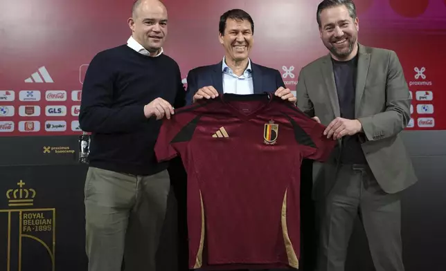 Newly appointed coach for Belgium's national team Red Devils, Rudi Garcia, center, holds a national team jersey as he poses with sports director Vincent Mannaert, right, and CEO Peter Willems after a media conference in Tubize, Friday, Jan. 24, 2025. (AP Photo/Virginia Mayo)