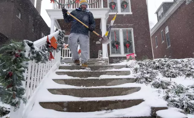 Paul Cullmann clears snow from steps outside his home Sunday, Jan. 5, 2025, in St. Louis. (AP Photo/Jeff Roberson)