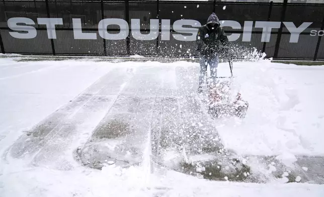 Andre Dresino uses a snow blower to clear a sidewalk Sunday, Jan. 5, 2025, in St. Louis. (AP Photo/Jeff Roberson)