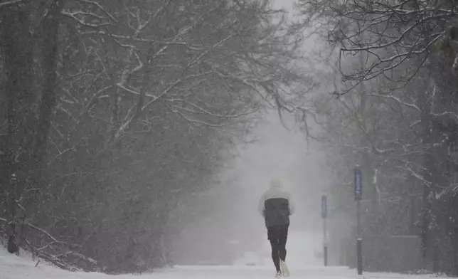 A person runs down a trail during a winter storm, Sunday, Jan. 5, 2025, in Cincinnati. (AP Photo/Joshua A. Bickel)