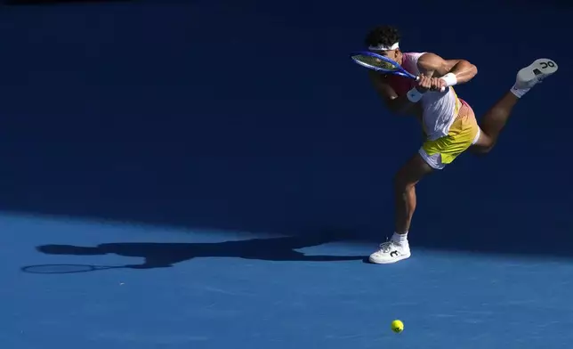 Ben Shelton of the U.S. plays a backhand return to Gael Monfils of France during their fourth round match at the Australian Open tennis championship in Melbourne, Australia, Monday, Jan. 20, 2025. (AP Photo/Manish Swarup)