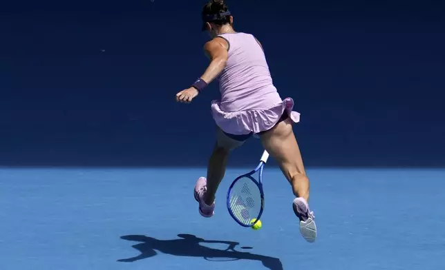 Belinda Bencic of Switzerland returns a shot between legs to Coco Gauff of the U.S. during their fourth round match at the Australian Open tennis championship in Melbourne, Australia, Sunday, Jan. 19, 2025. (AP Photo/Mark Baker)