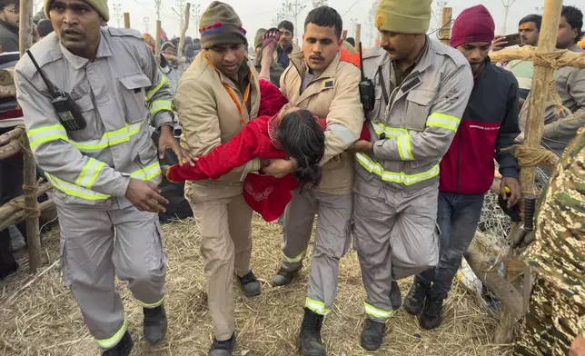 Security officers carry a woman out from the site of a stampede at the Sangam, the confluence of the Ganges, the Yamuna and the mythical Saraswati rivers, on "Mauni Amavasya" or new moon day during the Maha Kumbh festival, in Prayagraj, Uttar Pradesh, India, Wednesday, Jan. 29, 2025. (AP Photo/Rajesh Kumar Singh)