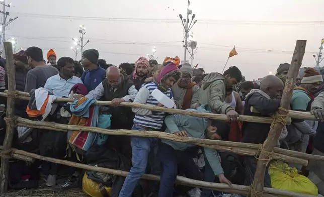 Hindu devotees try to cross a barricade to take a holy dip in the Sangam, the confluence of the Ganges, the Yamuna and the mythical Saraswati rivers, on "Mauni Amavasya" or new moon day during the Maha Kumbh festival in Prayagraj, India, Wednesday, Jan. 29, 2025. (AP Photo/Rajesh Kumar Singh)