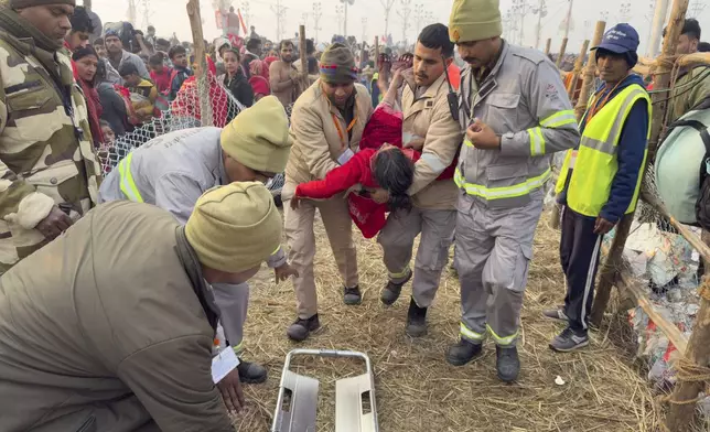 Security officers carry a woman out from the site of a stampede at the Sangam, the confluence of the Ganges, the Yamuna and the mythical Saraswati rivers, on "Mauni Amavasya" or new moon day during the Maha Kumbh festival, in Prayagraj, Uttar Pradesh, India, Wednesday, Jan. 29, 2025. (AP Photo/Rajesh Kumar Singh)