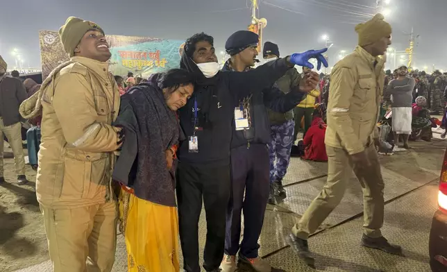 Security officers help a woman injured in a stampede by the banks of the Sangam, the confluence of the Ganges, the Yamuna and the mythical Saraswati rivers, on Mauni Amavasya' or new moon day during the Maha Kumbh festival, in Prayagraj, Uttar Pradesh, India, Wednesday, Jan. 29, 2025. (AP Photo/Rajesh Kumar Singh)