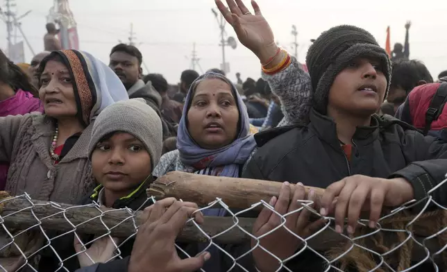 Hindu devotees stand behind a barricade and wait to take a holy dip in the Sangam, the confluence of the Ganges, the Yamuna and the mythical Saraswati rivers, on "Mauni Amavasya" or new moon day during the Maha Kumbh festival in Prayagraj, India, Wednesday, Jan. 29, 2025. (AP Photo/Rajesh Kumar Singh)