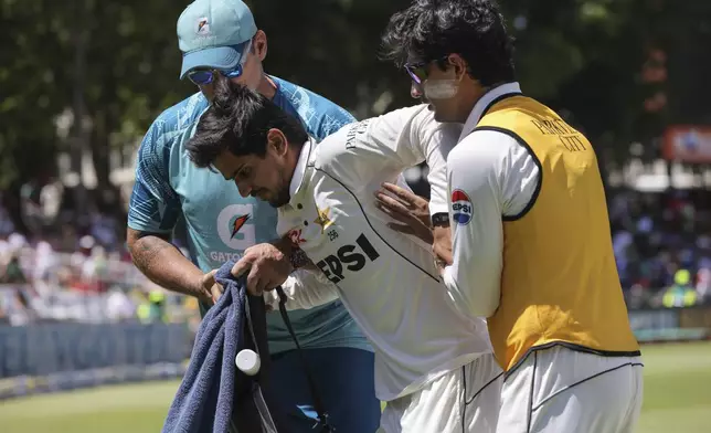 Pakistan's Saim Ayub is helped from the field after injuring his ankle while fielding the ball during the second test match between South Africa and Pakistan in Cape Town, South Africa, Friday, Jan. 3, 2025. (AP Photo/Halden Krog)