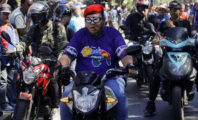 Government supporters ride past opponents of Venezuelan President Nicolas Maduro who are protesting the day before his inauguration for a third term in Caracas, Venezuela, Thursday, Jan. 9, 2025. (AP Photo/Cristian Hernandez)