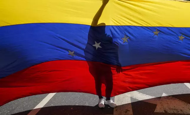 Opponents of Venezuelan President Nicolas Maduro display a Venezuelan flag during a protest the day before his inauguration for a third term in Caracas, Venezuela, Thursday, Jan. 9, 2025. (AP Photo/Ariana Cubillos)