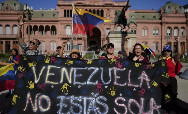 Opponents of Venezuelan President Nicolas Maduro hold a banner that reads in Spanish: "Venezuela, you're not alone" at Plaza de Mayo in Buenos Aires, Argentina, Thursday, Jan. 9, 2025, the day before Maduro's inauguration for a third term. (AP Photo/Natacha Pisarenko)