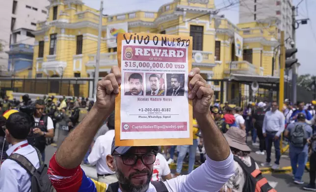 Venezuelan Tulio Rodriguez holds a wanted sign of Venezuelan President Nicolas Maduro that reads in Spanish: "Reward. Dead or alive" outside the Venezuelan embassy in Lima, Peru, Thursday, Jan. 9, 2025, the day before his inauguration for a third term. (AP Photo/Martin Mejia)