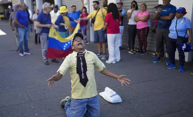 A man wearing the phrase in Spanish "Fight for freedom" kneels during a demonstration by opponents of Venezuelan President Nicolas Maduro the day before his inauguration for a third term in Caracas, Venezuela, Thursday, Jan. 9, 2025. (AP Photo/Matias Delacroix)